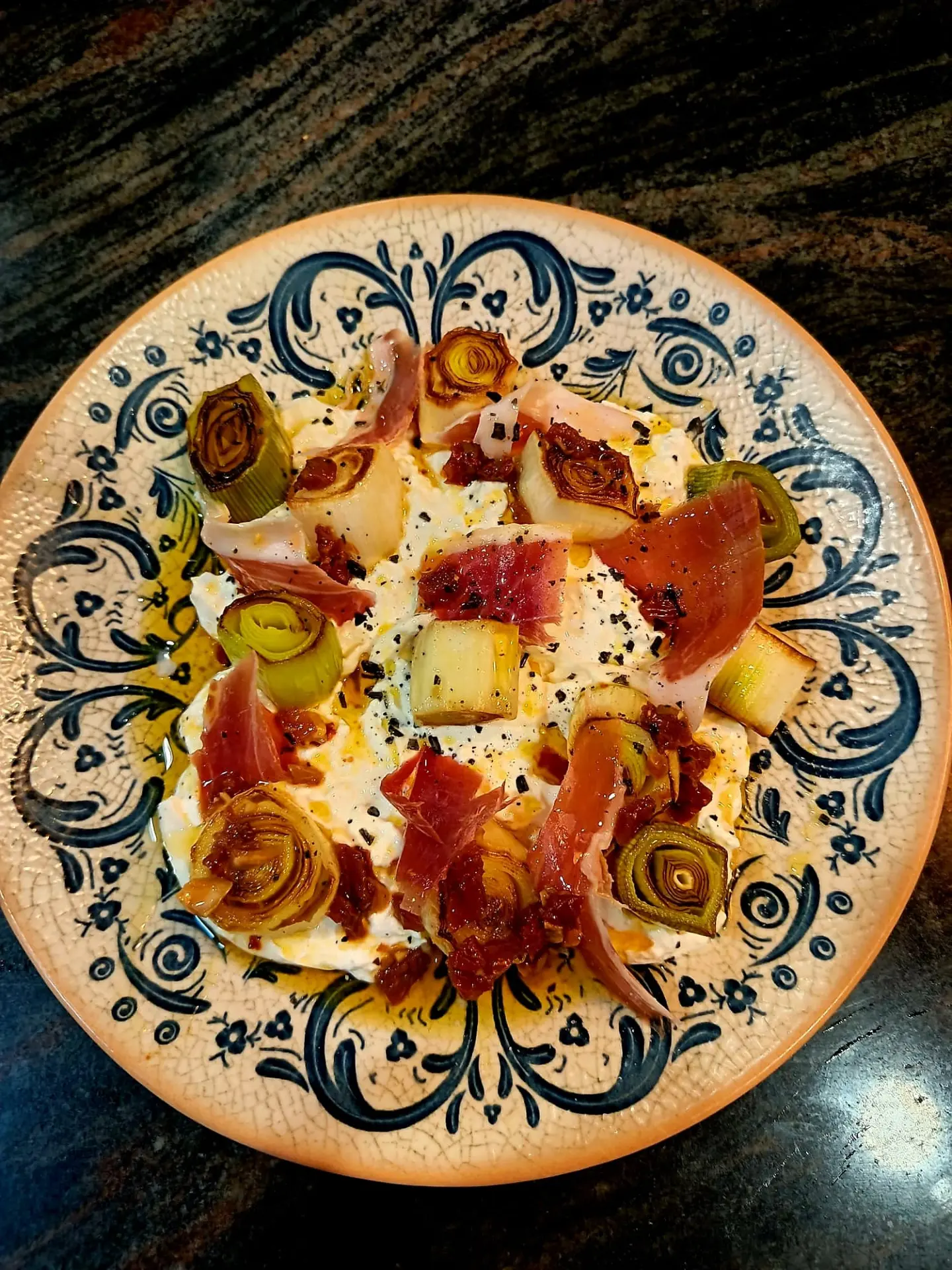Plato de burrata con puerro asado y jamón sobre loza artesanal
